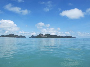 Ufukta bulutların ve turkuaz denizin birleştiği mavi gökyüzü.