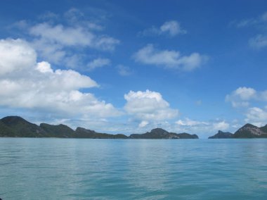 Ufukta bulutların ve turkuaz denizin birleştiği mavi gökyüzü.