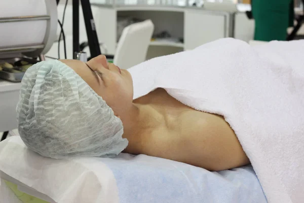 Seorang wanita muda berbaring di tempat tidur kosmetik di salon kecantikan . — Stok Foto