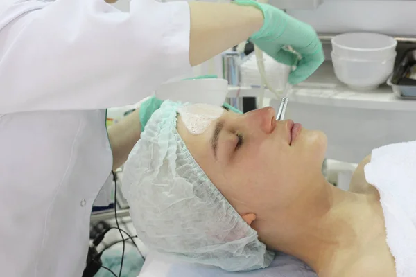 No salão de beleza uma jovem mulher está fazendo um peeling em seu rosto . — Fotografia de Stock