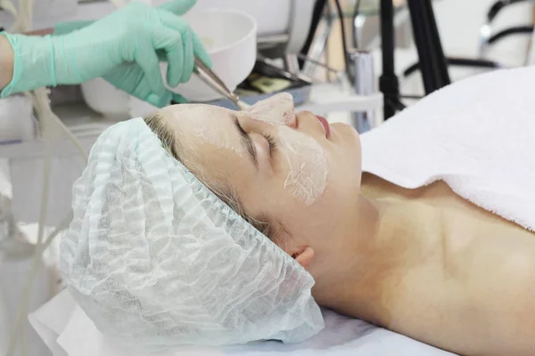 No salão de beleza uma jovem mulher está fazendo um peeling em seu rosto . — Fotografia de Stock