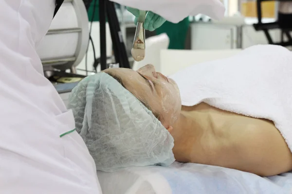 En el salón de belleza una joven está haciendo un peeling en su cara . —  Fotos de Stock