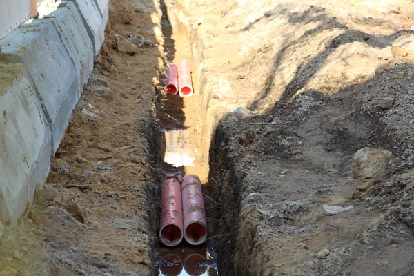 Laying pipes for hot and cold water. In the trench are plastic pipes.