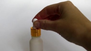 Bir kadın elinde gualinik sıvı ile Pipet. Beyaz bir şişeye damlayan bir damla. Cilt için altın parçacıkları ile serum. Sıvı altın parçacıkları ile cildi nemlendirin. 