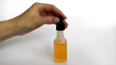 Şişe anti-aging sıvı. Cildi nemlendiren hyaluronik asitli serum. Güzel kadın el bir şişe bir pipet alır, damla görülebilir. Cilt bakımı kozmetik kavramı.