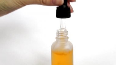 Şişe anti-aging sıvı. Cildi nemlendiren hyaluronik asitli serum. Güzel kadın el bir şişe bir pipet alır, damla görülebilir. Cilt bakımı kozmetik kavramı.