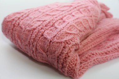 Sıcak pembe örme kazak beyaz bir arka plan üzerinde yatıyor.