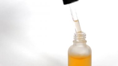 Şişe anti-aging sıvı. Cildi nemlendiren hyaluronik asitli serum. Güzel kadın el bir şişe bir pipet alır, damla görülebilir. Cilt bakımı kozmetik kavramı.