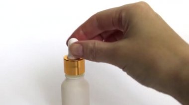 Bir dişi elinde altın bir sıvı olan pipet. Beyaz bir şişeye damlayan bir damla. Cilt için altın parçacıkları ile serum. Anti aging. Sıvı altın parçacıkları ile cildi nemlendirin.