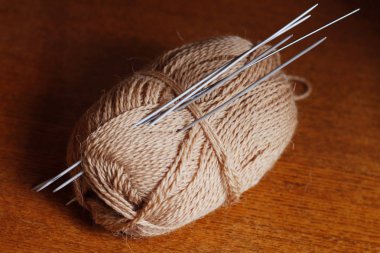 Skein iplik ve örgü iğneler. Örme. KANAVİÇE. Örme İğneler yün iplik sıkışmış. Kahverengi renk.