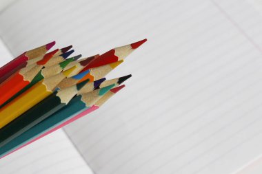 Renkli kalemler çizgili bir defterüzerinde yatıyor. Metin için bir yer var.