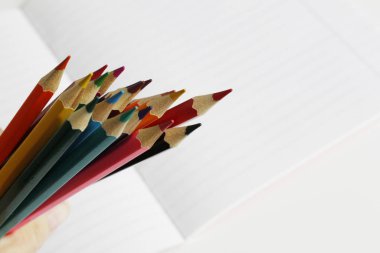 Renkli kalemler çizgili bir defterüzerinde yatıyor. Metin için bir yer var.