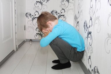 A young boy is crying in the hallway. Lonely boy. clipart