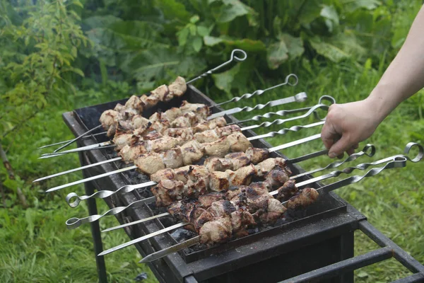 Cozinheiro cozinha espetos de churrasco. Kebab marinado é grelhado em carvão vegetal . — Fotografia de Stock