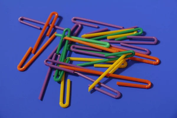 A lot of plastic tubules for drinks. Blue background. — Stock Photo, Image