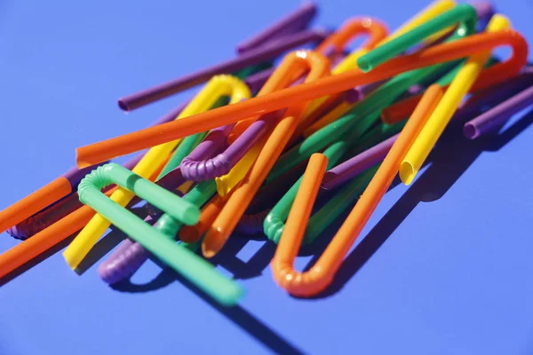 A lot of plastic tubules for drinks. Blue background. — Stock Photo, Image