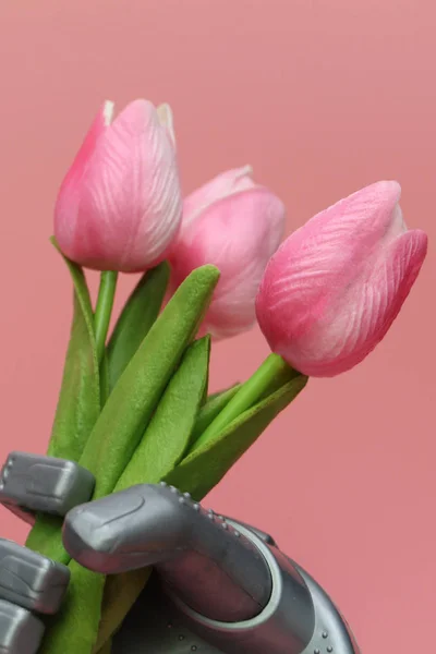 The robot gives flowers. The robots hand holds three tulips.