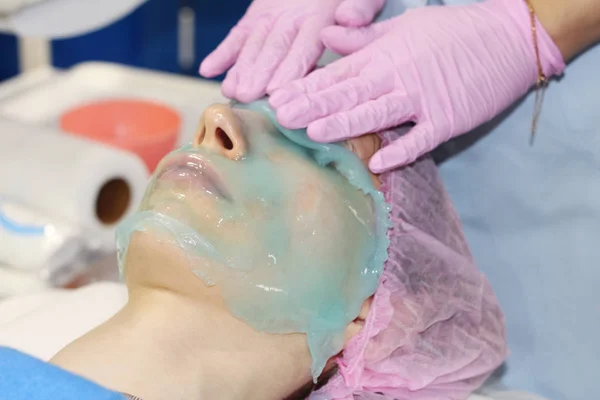 Un salón de belleza, un cosmetólogo elimina el polvo de una mascarilla facial pelada con alginato . —  Fotos de Stock