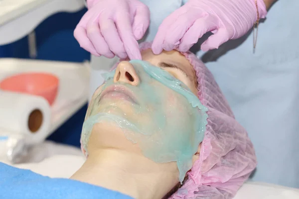Sebuah salon kecantikan, seorang ahli kosmetologi menghilangkan bubuk dari masker wajah alginat . — Stok Foto