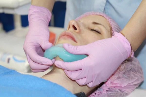 Um salão de beleza, um cosmetologista remove o pó de uma máscara facial de descascamento de alginato . — Fotografia de Stock