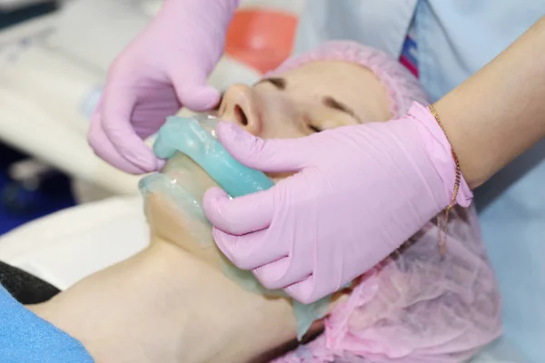 Un salón de belleza, un cosmetólogo elimina el polvo de una mascarilla facial pelada con alginato . —  Fotos de Stock