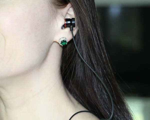 Musical headphones in the ear of a young woman. — Stock Photo, Image