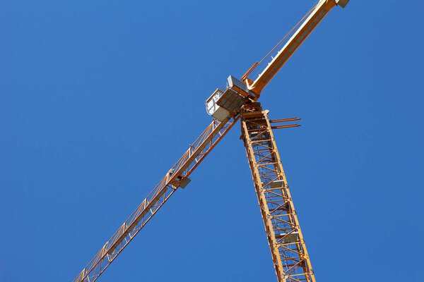 Construction crane on a background of blue sky. The construction of new homes. The concept of resuming construction sites. New apartments.