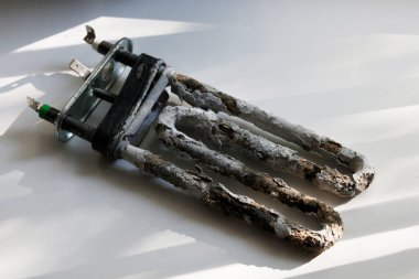 Çamaşır makinesi için eski bir kireçtaşı ısıtıcısı. Günlük hayatta kullanılan bir çamaşır makinesi için yedek parça. Çamaşır makinelerinin tamiri. Eski elektrikli su ısıtıcısı.