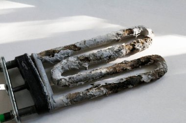 Çamaşır makinesi için eski bir kireçtaşı ısıtıcısı. Günlük hayatta kullanılan bir çamaşır makinesi için yedek parça. Çamaşır makinelerinin tamiri. Eski elektrikli su ısıtıcısı.