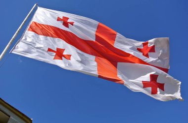 Gürcü bayrağı mavi gökyüzü karşı esintiyle sallayarak 