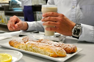 Valencia, İspanya-Nisan 22, 2015: bir kafede masa üzerinde farton denilen çöl ile sarı somun saz yapılan geleneksel Valencian içecek cam tutan adam
