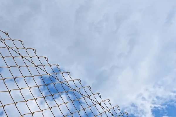 Chain link fence on blue cloudy sky background