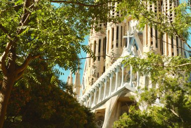 Yeşil ağaçların arkasındaki parktan Sagrada Familia kilisesine gidin. Barselona, İspanya