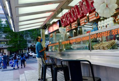 Madrid / İspanya: 1 Ekim 2020: Korumacı maskeli orta yaşlı bir adam kentin kapatılmasından önce banliyödeki yerel bir satıcıdan churros adında İspanyol geleneksel sokak yemekleri satın alıyor.