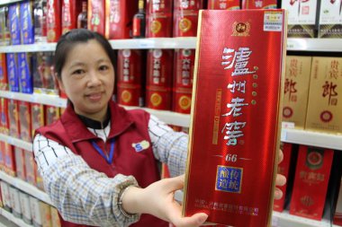 --FILE--A saleswoman displays a bottle of Chinese fiery liquor Luzhou Laojiao at a supermarket in Nantong city, east China's Jiangsu province, 10 June 2016 clipart