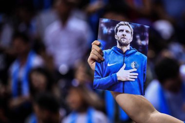 A Chinese basektball fan shows a photo of Dirk Nowitzki of Dallas Mavericks as they compete against Philadelphia 76ers during the Shenzhen match of the NBA China Games in Shenzhen city, south China's Guangdong province, 8 October 2018 clipart