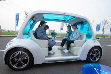 Chinese volunteers take an UISEE self-driving vehicle at the intelligence experience zone for the upcoming United Nations World Geospatial Information Congress (UNWGIC) in Deqing county, Huzhou city, east China's Zhejiang province, 20 November 2018.  clipart