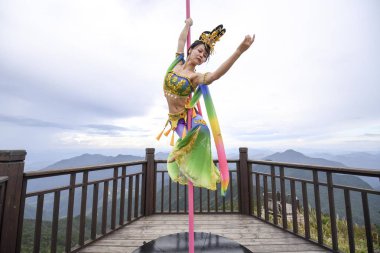 Tourists watch Chinese enthusiasts dressed in traditional costumes featuring the shape of Chinese goddess of the Moon Chang'e performing pole dance skills on the top of Longquan Mountain in Lishui city, east China's Zhejiang province, 20 September 20 clipart