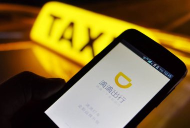 A mobile phone user uses the mobile app of taxi-hailing and car service Didi Chuxing on his smartphone in Ji'nan city, east China's Shandong province, 9 September 2015 clipart