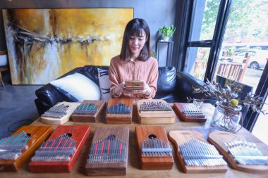 Chinese music lover April Yang poses for photos with redesigned kalimbas, or thumb pianos, at a workshop in Jiaxing city, east China's Zhejiang province, 24 August 2018 clipart