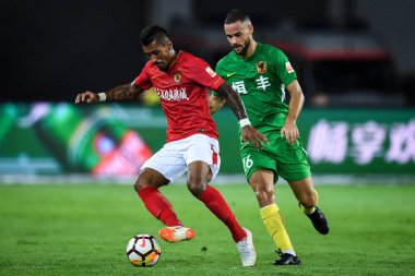 Brazilian football player Paulinho, left, of Guangzhou Evergrande Taobao passes the ball against Spanish soccer player Mario Suarez of Guizhou Hengfeng in their 12th round match during the 2018 Chinese Football Association Super League (CSL) in Guang