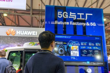  visitor looks at a signboard of Future Factory & 5G at the stand of Huawei during the 2018 Mobile World Congress (MWC) in Shanghai, China, 29 June 2018 clipart