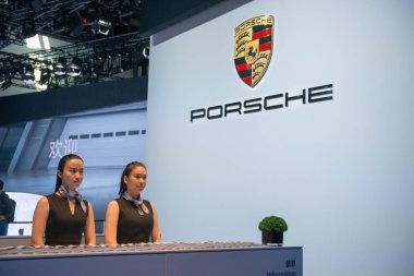 Chinese employees are seen at the stand of Porsche during the 15th Beijing International Automotive Exhibition, also known as Auto China 2018, in Beijing, China, 25 April 2018. clipart