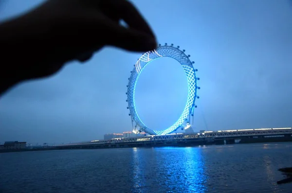 A local resident poses for a creative photo with a "big ring", Bailang River Bridge Ferris Wheel, the world's largest spokeless Ferris wheel with grid design, on the Bailang River in Weifang city, east China's Shandong province, 18 May 2018 — Stock Image Local Resident Poses Creative Photo Big Ring Bailang River Bridge Stock Picture