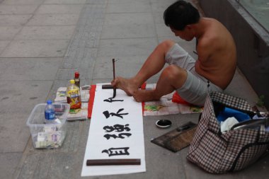 The handicapped Chinese man without hands uses his toes to write calligraphy of 