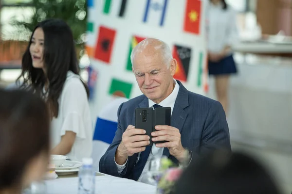 George Papandreou, former Prime Minister of Greece, takes photos during a meal at the campus of the Wuhan University of Engineering Science in Wuhan city, central China's Hubei province, 29 May 2018.