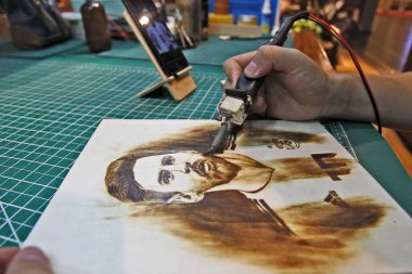 27-year-old Chinese man Peng Fang works with an art work of pyrography at his shop in Xi'an city, northwest China's Shaanxi province, 23 July 2018. clipart