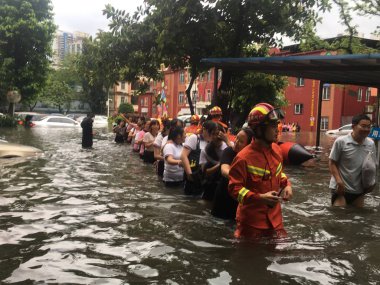 Chinese rescuers evacuate local residents from flooded areas caused by a heavy rainstorm and Typhoon Ewiniar in Guangzhou city, south China's Guangdong province, 8 June 2018 clipart