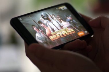 A Chinese mobile game player plays Tencent's multiplayer online battle royale game PlayerUnknown's Battlegrounds, on his smartphone in Ji'nan city, east China's Shandong province, 8 February 2018 clipart