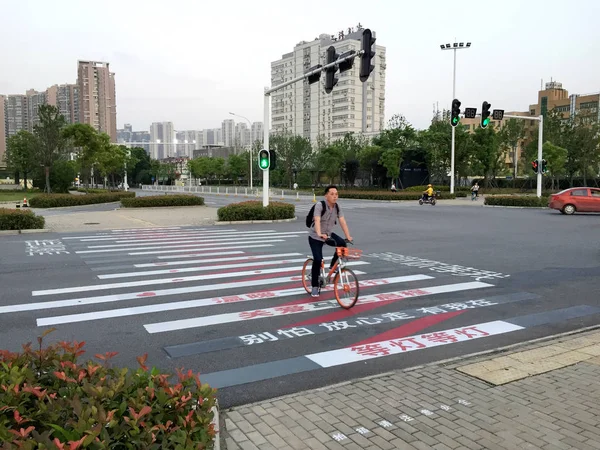 2018年5月23日 在中国中部的湖北省武汉市 一名骑自行车的人骑着一些关于道路安全的甜美标语 骑车经过斑马线 — 图库照片